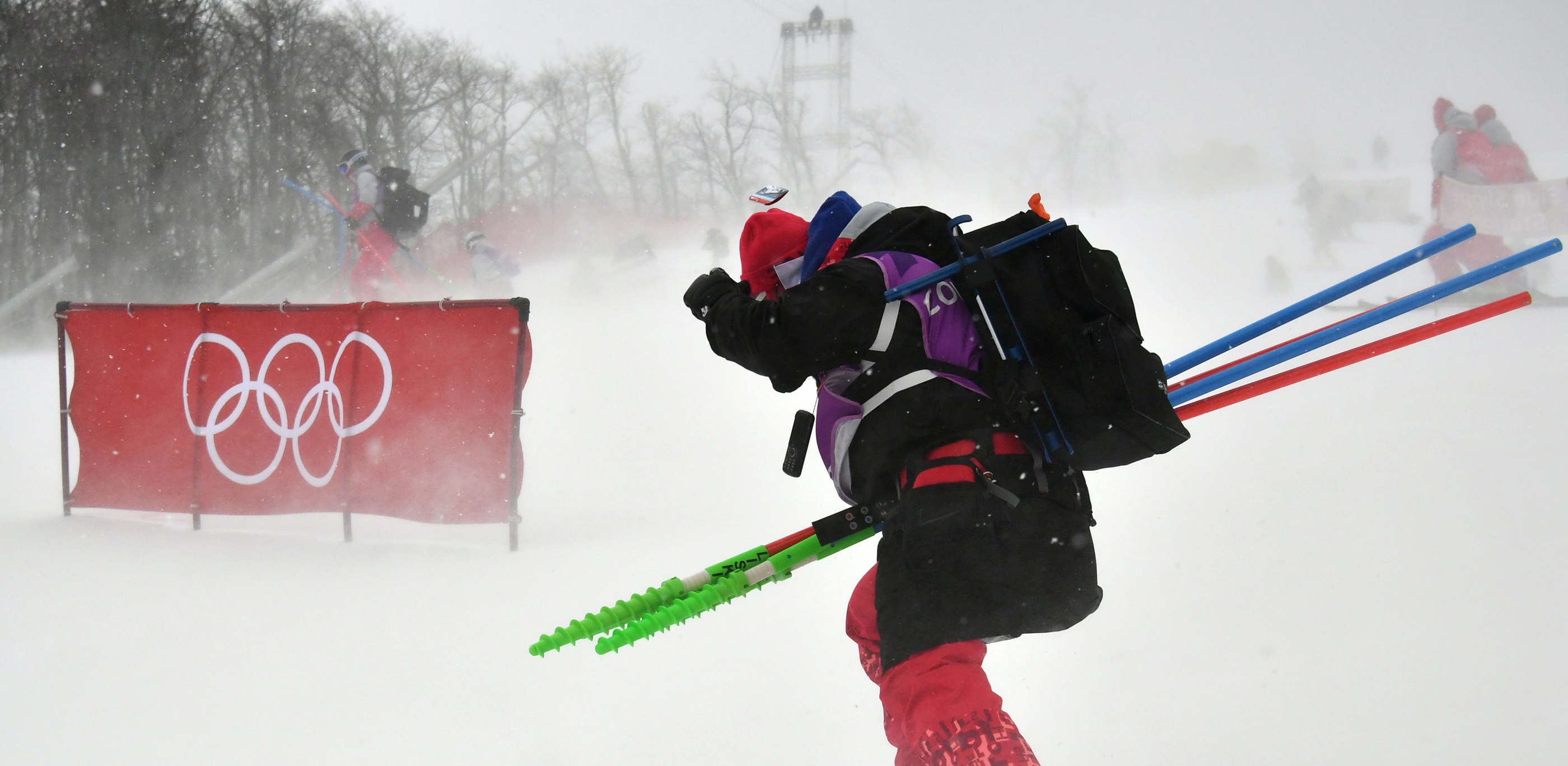 A volunteer skis past a barrier bearing the Olympic rings as the start of the slalom course Wednesday. (Getty Images/AFP – Fabrice Coffrini)