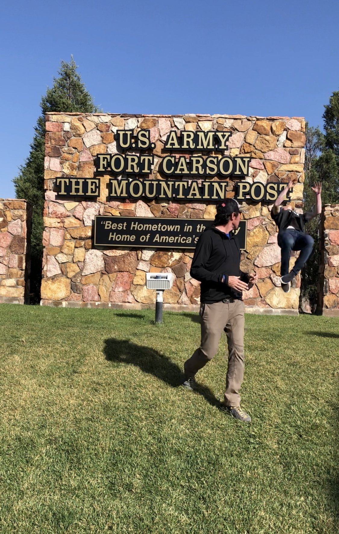 Jason Wolle backflipping in front of the Fort Carson sign.