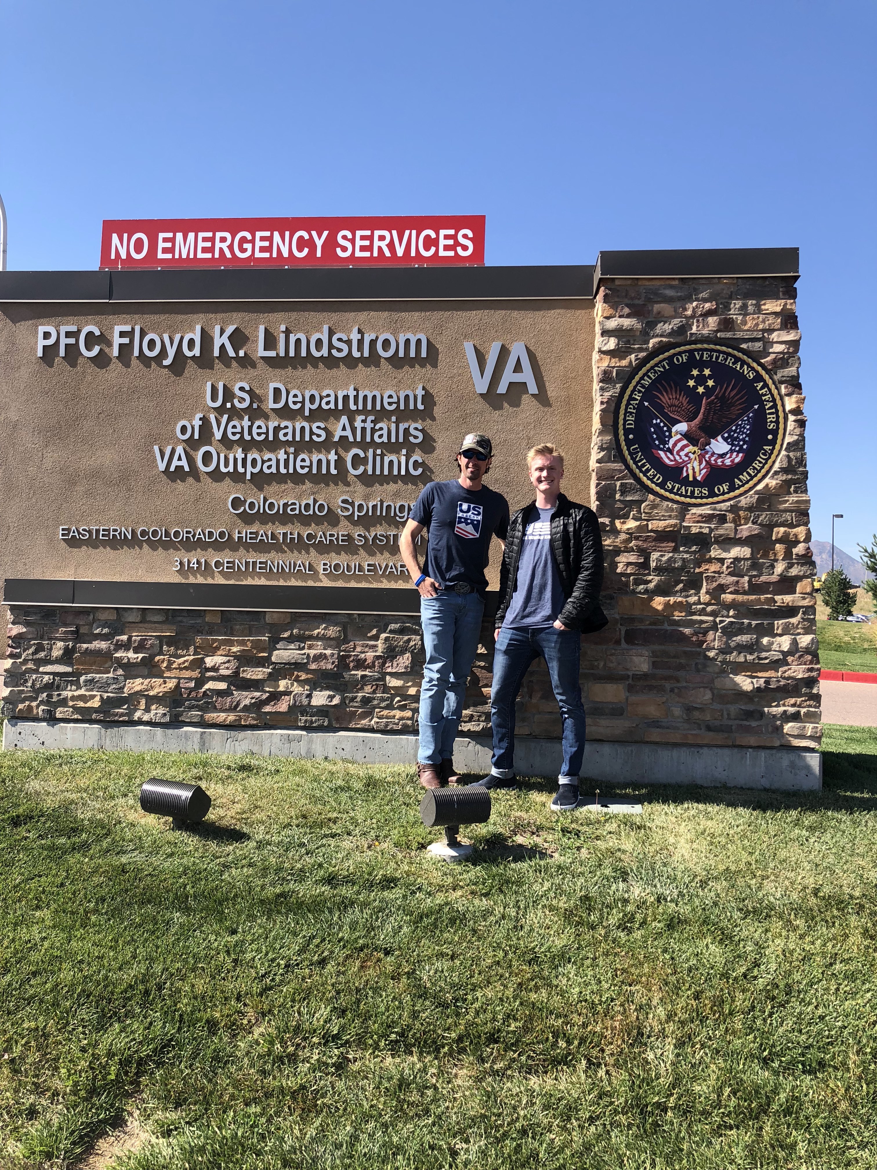 Jason Wolle and Jesse Stewart in front of VA sign in Fort Carson.