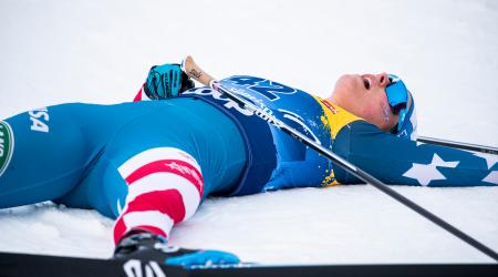 An exhausted Jessie Diggins lies on the snow after crossing the finish line in Tuesday's third stage of the Tour de Ski.  (www.nordicfocus.com. © Modica/NordicFocus)
